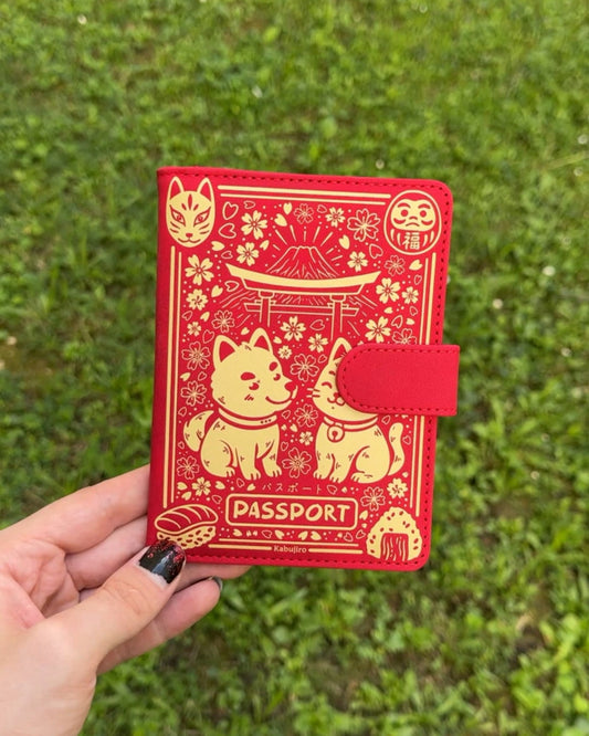 Red passport holder with gold designs held in front of a grassy background